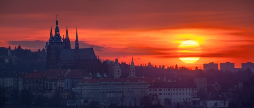 Fotografie – Rudý kotouč slunce za Pražským hradem